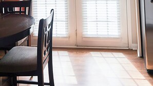 A kitchen with a dining table and chairs, a refrigerator, and a double door with blinds.