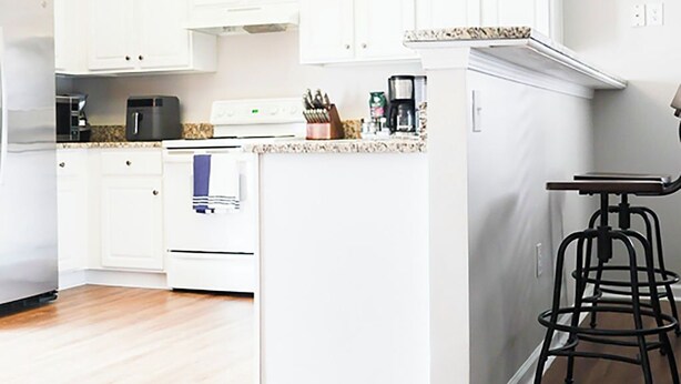 A modern kitchen with white cabinetry, a central island, and a bar stool.