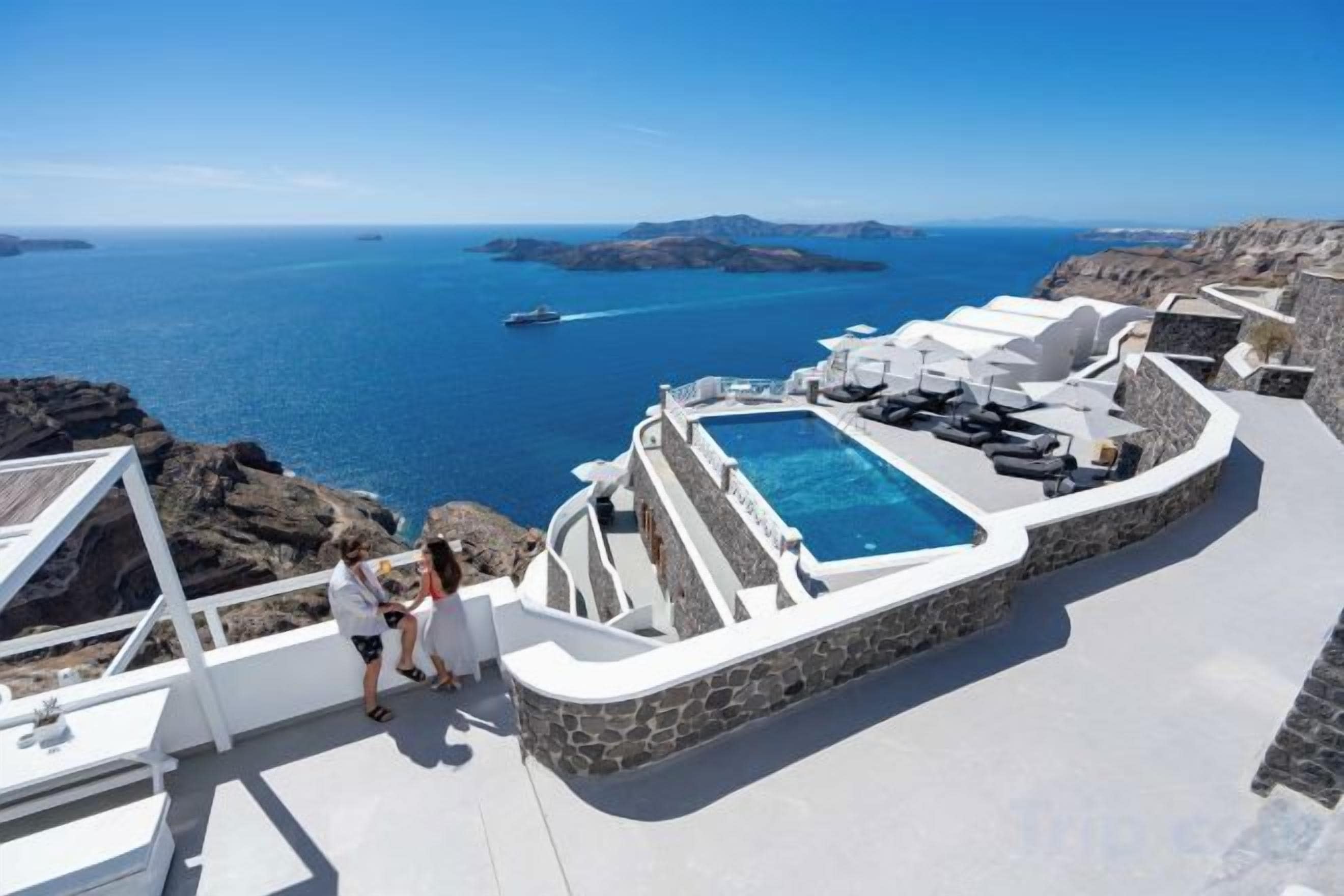 Un espace piscine offrant une vue sur la mer et un paysage rocheux.