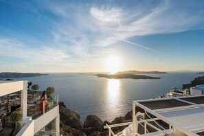 A coastal view with a clear sky, a body of water, and a distant sun setting or rising.