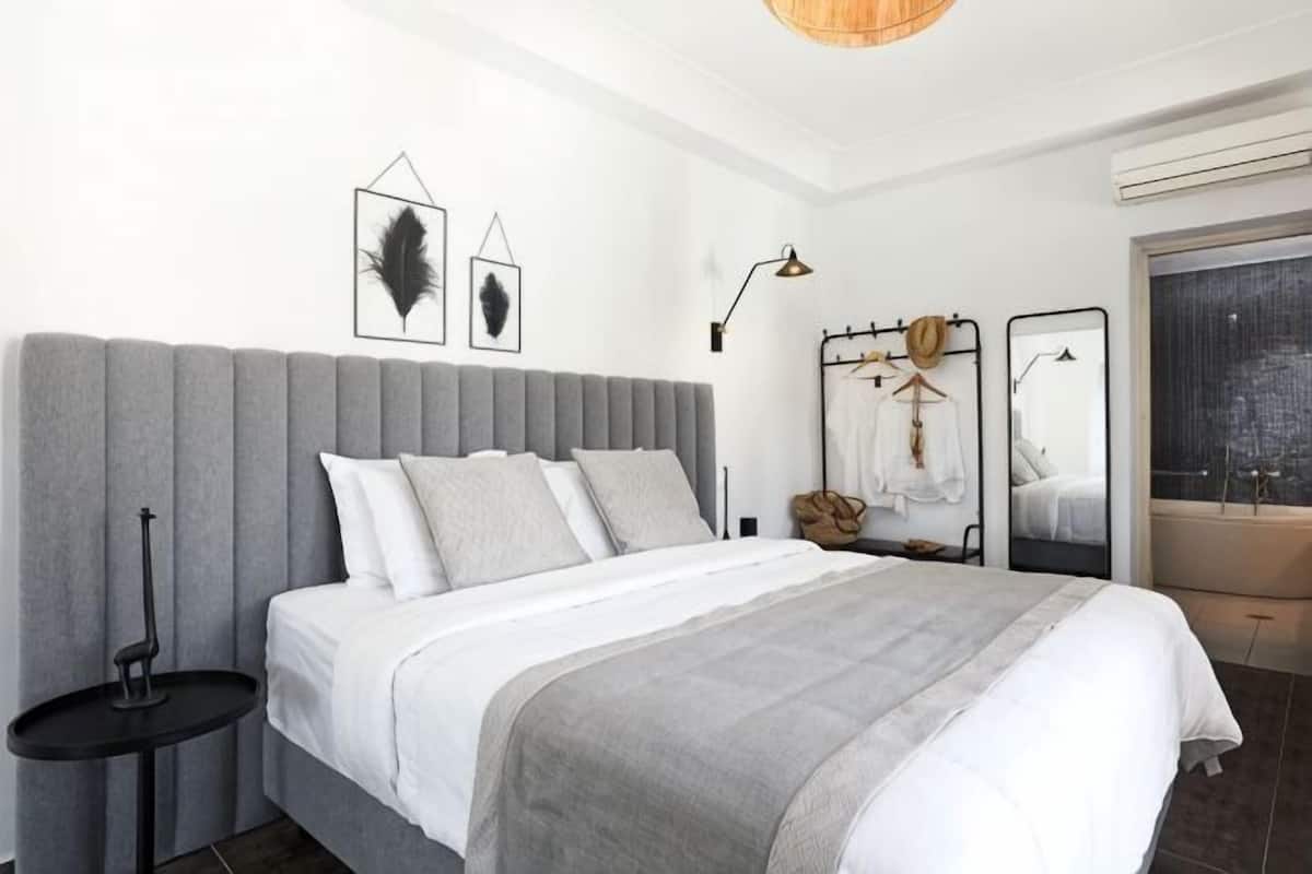 Une chambre moderne avec un grand lit, des tables de chevet, une armoire et une fenêtre donnant sur un beau paysage.