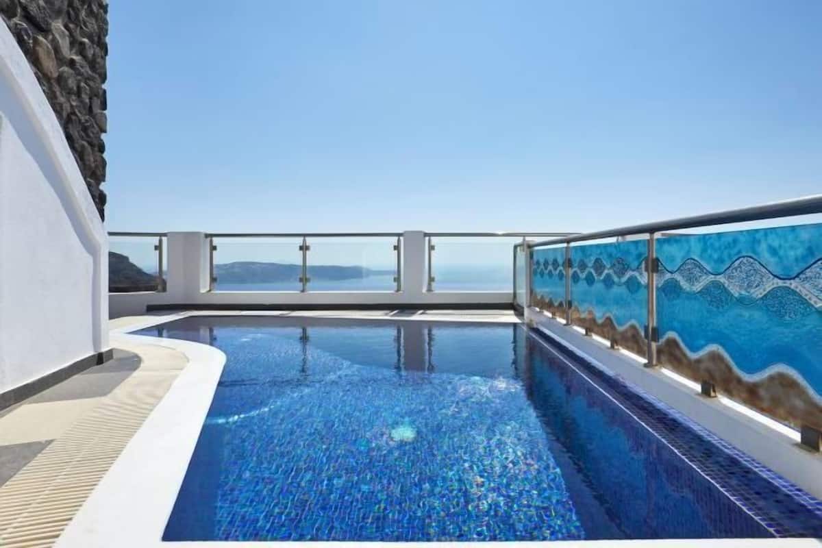 Une piscine offrant une vue dégagée sur la mer et les montagnes en arrière-plan.