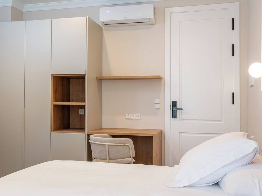 A bedroom with a bed, a desk, and a wardrobe.