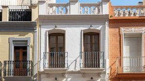 Un immeuble à plusieurs étages doté de balcons, d’une porte en bois et d’un portail en métal.