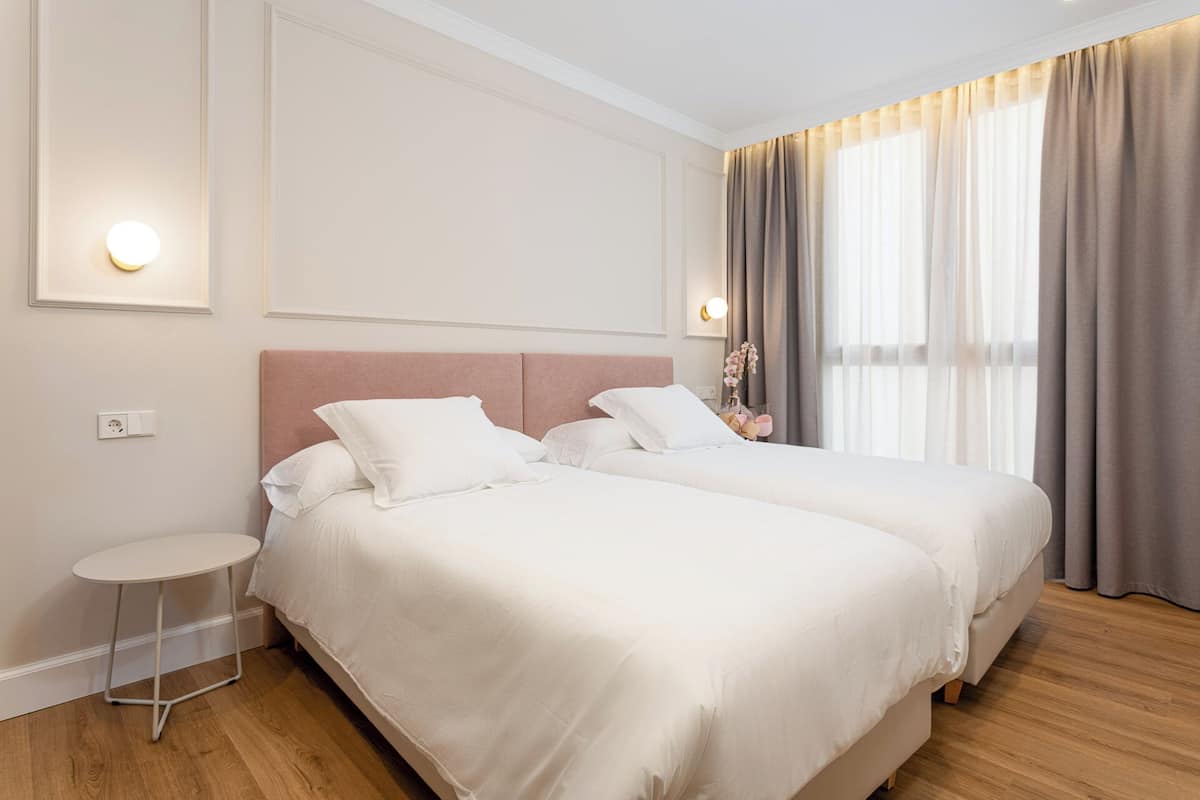 A hotel room with two beds, a small round table, and a nightstand.