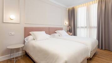 A hotel room with two beds, a small round table, and a nightstand.