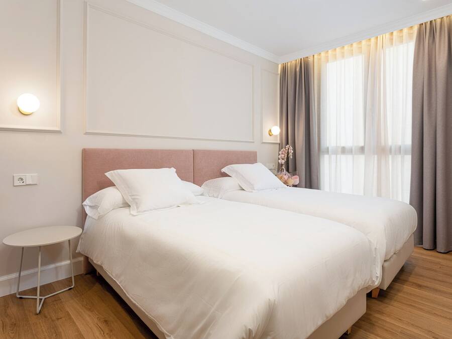 A hotel room with two beds, a small round table, and a nightstand.