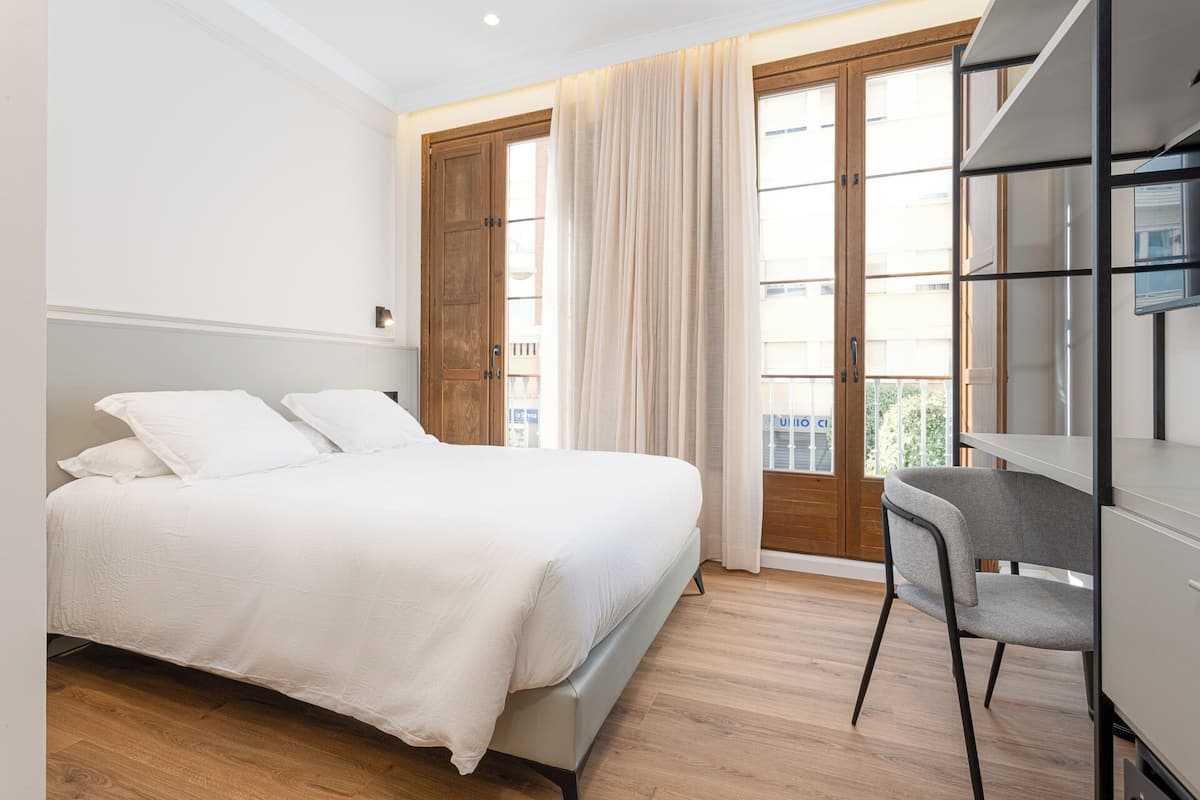 A bedroom with a bed, a desk, and a chair.