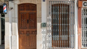 Une entrée d’immeuble avec une porte double en bois et un portail en métal.