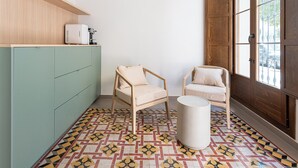Une pièce avec deux chaises en bois, un meuble vert et un sol à motifs.