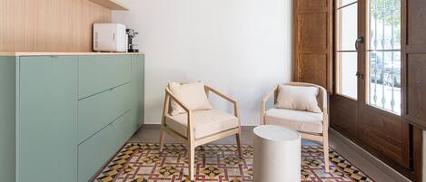 A room with two wooden chairs, a green cabinet, and a patterned floor.