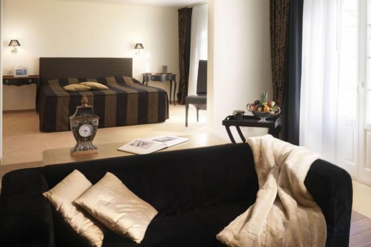 A hotel room with a bed, a sofa, a coffee table, and a clock.