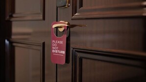 Una porta con un cartello che riporta 'PER FAVORE NON DISTURBARE'.