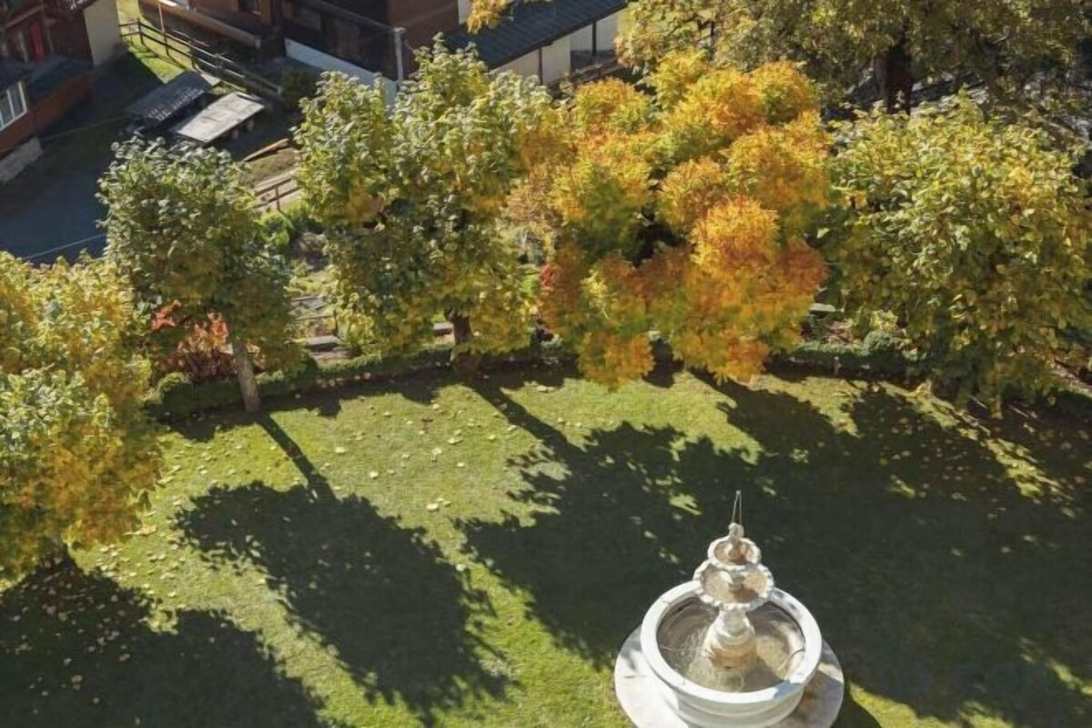 A courtyard with a fountain, surrounded by trees with autumn foliage.