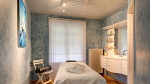 Una stanza con un letto, una sedia, una finestra con persiane, un termosifone e uno scaffale con articoli da toilette.