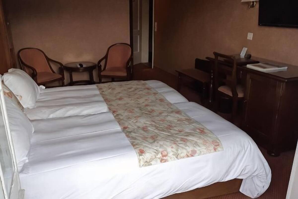 Camera d'albergo con un letto grande, due poltrone, un tavolino e una scrivania con sedia.