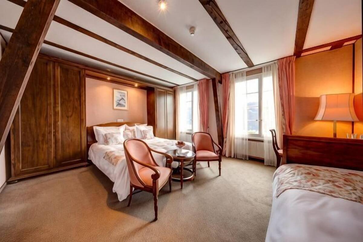 Una camera da letto con un letto, due sedie, un tavolino e una finestra.