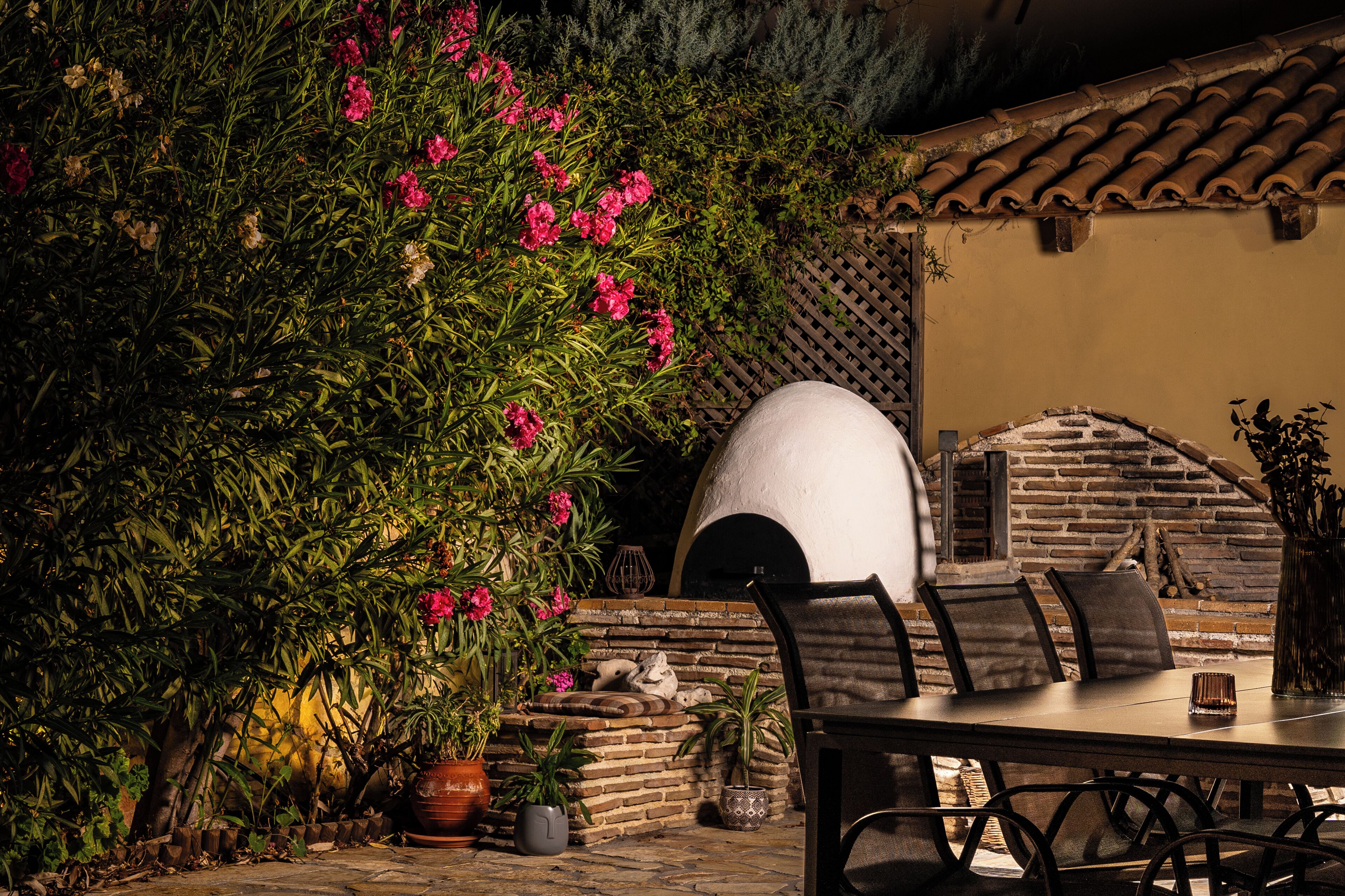An outdoor dining area with a brick wall, a stone bench, and a potted plant.