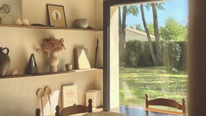 Un comedor con una mesa dispuesta para cuatro, una lámpara colgante y vista a un jardín a través de un ventanal.