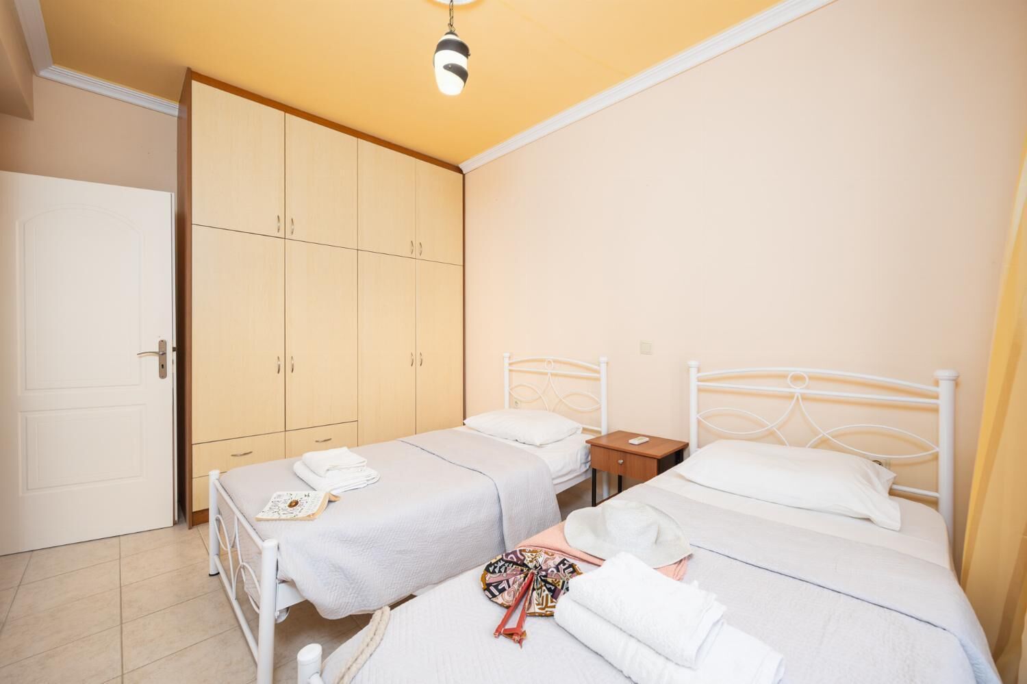 Un dormitorio con dos camas individuales, un armario y una mesita de noche con lámpara.