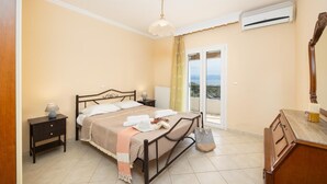 Un dormitorio con cama, mesita de noche, cómoda y vistas al balcón exterior por una puerta corrediza.