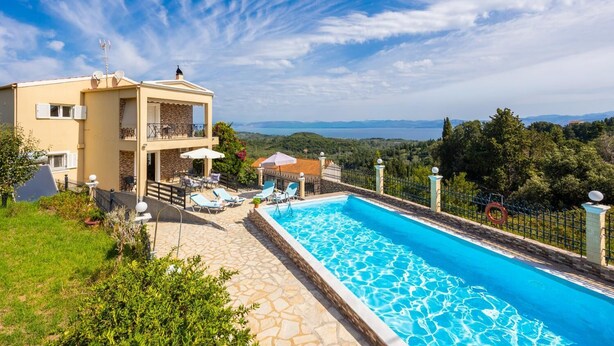 Un edificio de dos pisos con piscina, mobiliario exterior y vistas al paisaje.