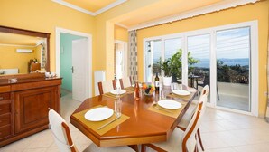 Un comedor con una mesa de madera dispuesta para cuatro, un espejo grande y vistas al exterior a través de un ventanal corredero.