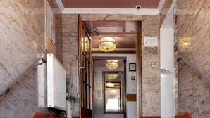 Corredor com piso de mármore, um candelabro, um radiador e uma placa indicando área para fumantes.