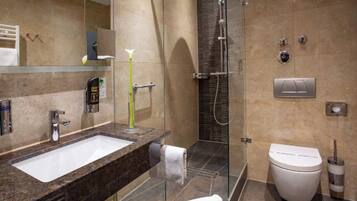 A modern bathroom with a marble sink, a glass shower enclosure, a toilet, and a towel.