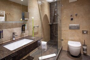 A modern bathroom with a marble sink, a glass shower enclosure, a toilet, and a towel.