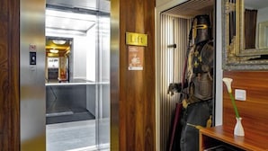 Um elevador com o letreiro 'Lift', uma parede de madeira e um espelho com moldura decorativa.