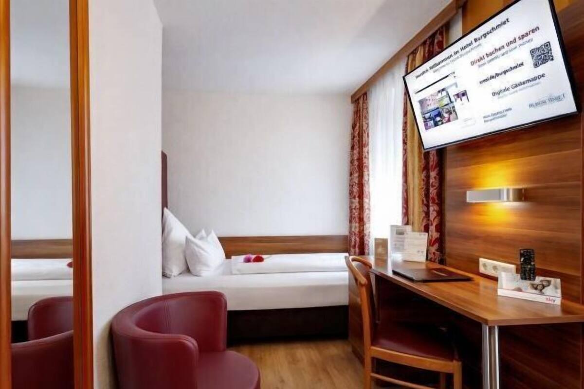 Une chambre d’hôtel avec un lit, un bureau et une chaise, une télévision et un mur en bois.