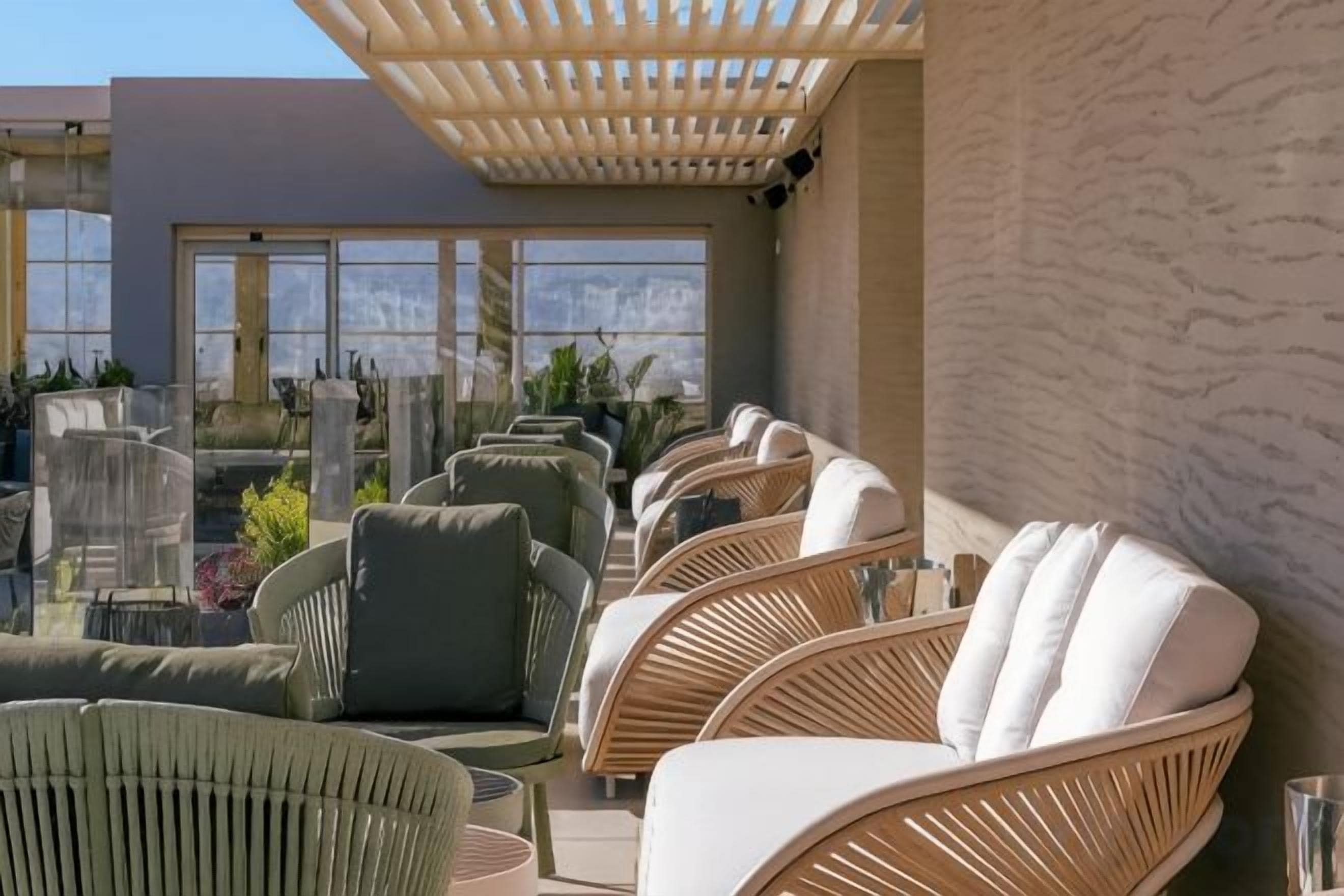 A rooftop terrace with wicker furniture and a pergola.