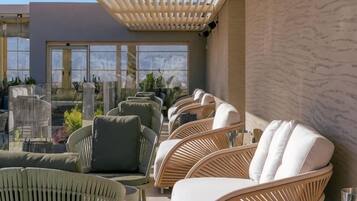 A rooftop terrace with wicker furniture and a pergola.