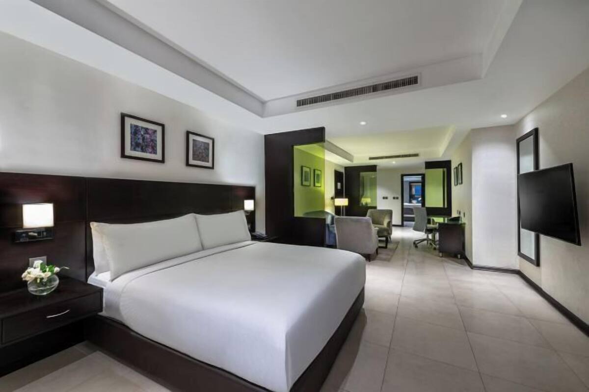 Une chambre d’hôtel avec un grand lit, des tables de chevet, un bureau, une chaise et un téléviseur.