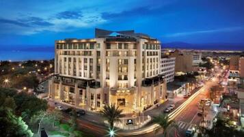 A multi-story hotel with a central courtyard, surrounded by a cityscape and a body of water.