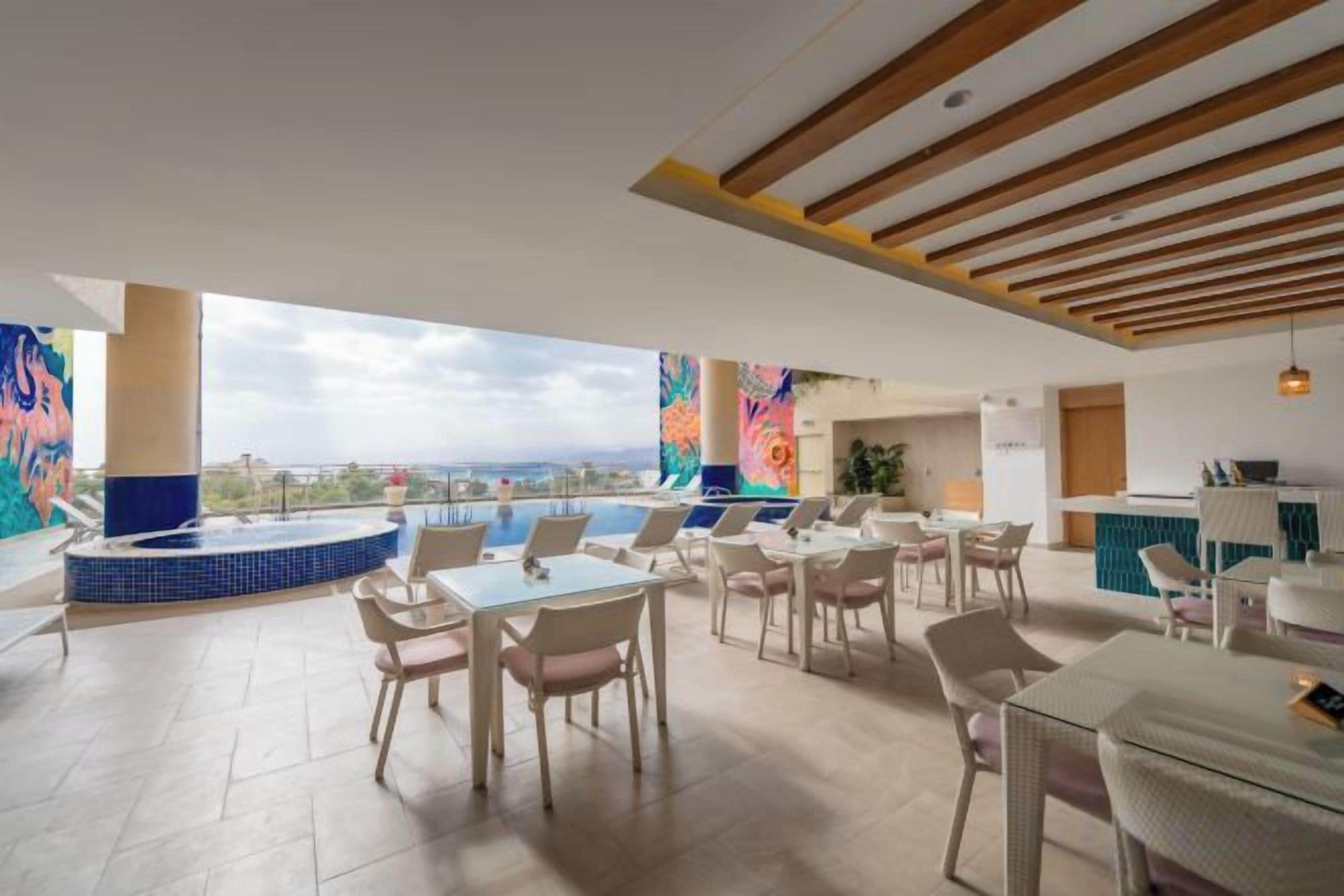 A rooftop terrace with a pool, lounge chairs, and a view of the city.