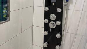 En dusch med flera duschmunstycken, ett handhållet duschhuvud och en flexibel duschslang.