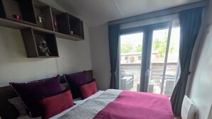 A hotel room with a large bed, a balcony with a view, and a shelf with decorative items. - Beach house on the Rhön beach with whirlpool (Wartmannsroth)