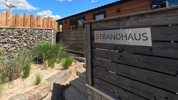 A wooden fence with a sign reading "STRANDHAUS" and a seagull perched on top. - Beach house on the Rhön beach with whirlpool (Wartmannsroth)