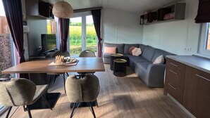 A modern kitchen with a dining area, a sofa, and a view of a garden. - Beach house on the Rhön beach with whirlpool (Wartmannsroth)
