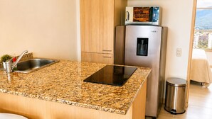 A modern kitchen with a granite countertop, stainless steel appliances, and wooden cabinets.