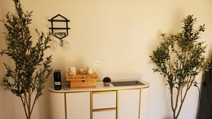 Eine Ecke mit einem weißen Korpus mit Goldzierleisten, einer Wandleuchte und zwei Topfpflanzen.