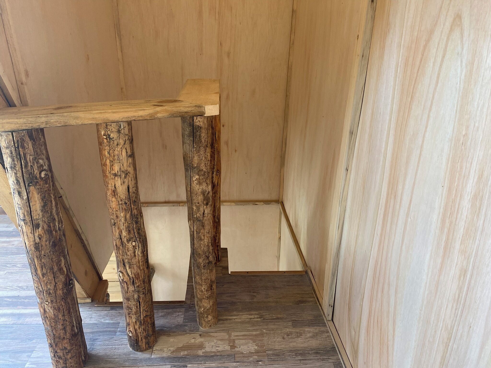 Una mesa de madera rústica con cuatro patas, ubicada frente a una pared y un suelo de madera.