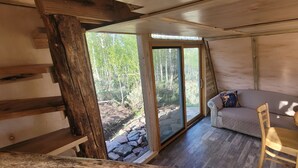A cabin interior with a stone foundation, wooden walls, a cushioned seating area, and a wooden table. - Pronghorn Point Cabin@22 West Cabins 18miles from Walden 80 miles from Steamboat (Walden)