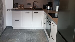 A modern kitchen with white cabinets, a stainless steel refrigerator, and a coffee maker.