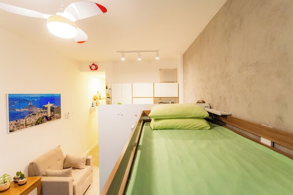 Relax in a cozy space with a single bed, sofa, and wall-mounted TV.