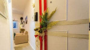 A hallway with a door decorated with a red ribbon, a gold bow, and a green fern. There is a beige sofa in the background. - SUH Copacabana 79 New Beach (Rio de Janeiro)