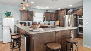 Una cocina moderna con armarios de madera, electrodomésticos de acero inoxidable e iluminación colgante.