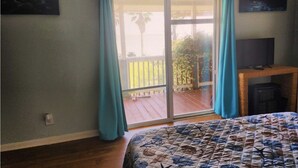 Un dormitorio con una cama grande, un ventanal corredero a un balcón y una chimenea.
